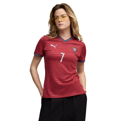A woman wearing a red Portugal soccer jersey with the number 7 and yellow-tinted sunglasses, posing against a solid black background.