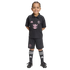A young child smiling in a black Inter Miami CF soccer kit with pink logos, matching shorts, and tall socks, set against a black background.
