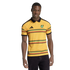 A man modeling a yellow Jamaica soccer jersey with a black polo collar and horizontal green, red, and black striped patterns against a black background.