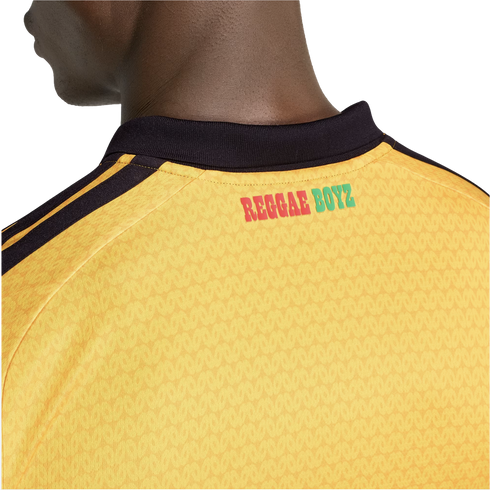 Close-up of the back of a yellow jersey with black stripes on the shoulders and "REGGAE BOYZ" printed in red and green below a black collar.
