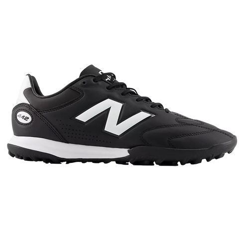 A black New Balance 442 turf soccer shoe featuring a large white 'N' logo and white midsole detail, shown from a side profile against a black background.