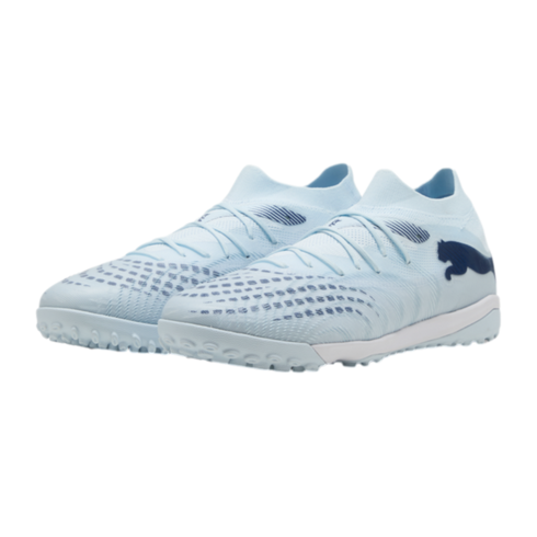 A pair of light blue Puma turf soccer shoes with dark blue details and a white midsole, displayed against a black background.
