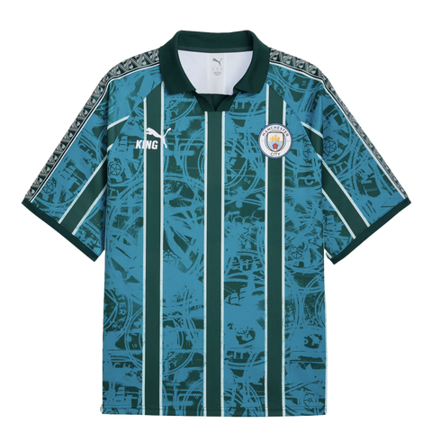 Manchester City Puma King jersey with teal and dark green vertical stripes over a distressed crest graphic. Features a dark green collar and patterned trim on the shoulders and sleeves.