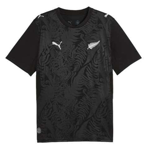A black Puma t-shirt with a tonal fern pattern, featuring white Puma cat logos on the chest and shoulders, and a white silver fern emblem on the left chest.