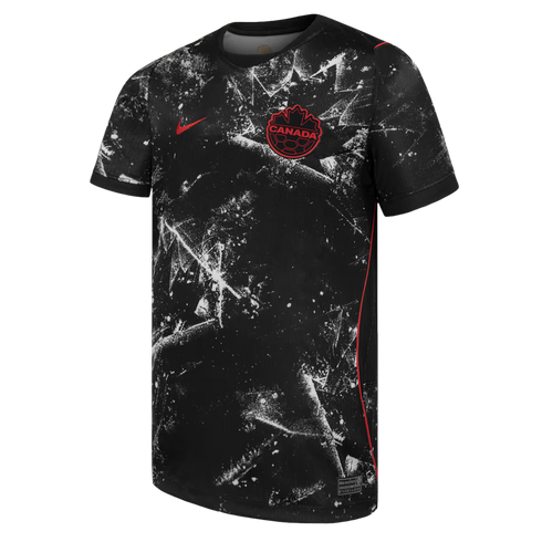 A black short-sleeved Canada national soccer team jersey featuring a white splatter pattern that forms large, stylized maple leaf motifs. A red Nike swoosh is on the right chest, and a red and black circular Canada Soccer crest with "CANADA" text is on th
