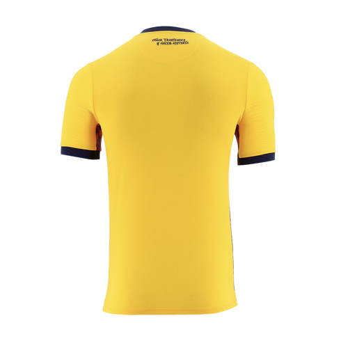 A solid yellow, short-sleeved sports jersey is shown from the back against a black background. It features navy blue trim on the collar and sleeve cuffs, and dark blue text printed on the upper back near the collar that reads "SOÑAR, TRASCENDER Y HACER HI