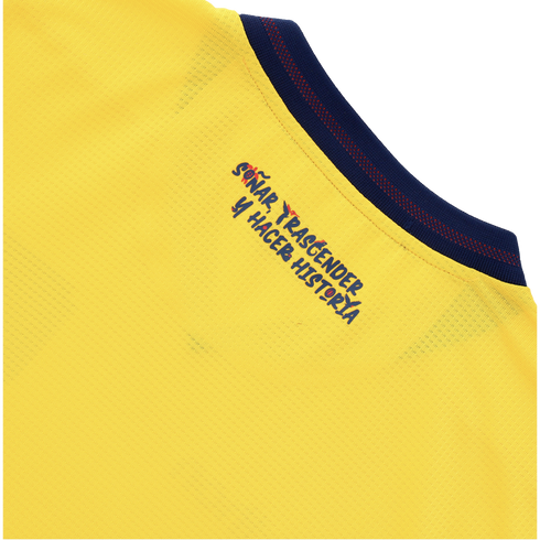 Close-up of a yellow sports jersey with navy blue stylized text that reads "SOÑAR, TRASCENDER Y HACER HISTORIA." Small red graphic accents are integrated into some of the letters, and a dark blue ribbed collar is visible at the top right.