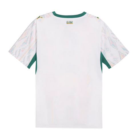 The back of a white short-sleeved jersey featuring a green crew neckline and underarm panels. The sleeves are covered in a colorful, geometric pattern, and a small logo on the upper back reads “LES LIONS DU SÉNÉGAL.”