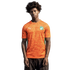A medium shot of a young man with dark, curly hair wearing an orange Puma soccer jersey for the Côte d'Ivoire national team. The jersey features an all-over tonal leopard-print pattern, a green and white national crest on the left chest, and a white Puma