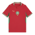A red Morocco national football team home jersey by Puma, featuring the national team crest in the center, golden Puma logos on the right chest and shoulders, and green accents on the sides and sleeves. Intricate patterned trim adorns the collar and sleev
