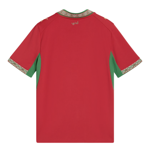 A back view of a red short-sleeved Morocco national team jersey. It features green panels under the arms and a green, white, and red geometric pattern on the collar and sleeve cuffs. Gold Puma logos are on the shoulders, and gold Arabic text is centered b