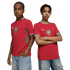 Two young people pose side-by-side against a black background, wearing red Moroccan national football team jerseys and light-wash denim jeans.
