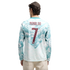Rear view of a man wearing a long-sleeved teal and white jersey featuring a wavy, ocean-inspired graphic. The name "RONALDO" and the number "7" are printed on the back in maroon. He is also wearing light-colored trousers against a solid black background.