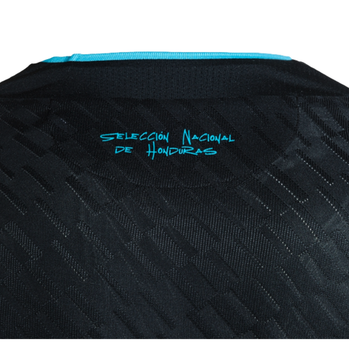 A close-up of the upper back of a black textured jersey, featuring a turquoise trim at the collar and the words "SELECCIÓN NACIONAL DE HONDURAS" printed in stylized turquoise text.