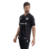 A man models an Oakland Roots SC soccer jersey against a solid black background. The black V-neck jersey features tonal grey wavy patterns on the front, textured scale-like patterns on the sleeves, the team's circular crest on the chest, and an Anthem spo