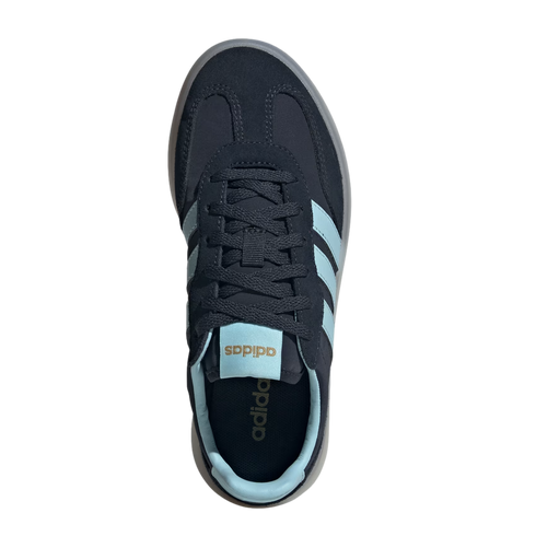 An overhead view of a navy blue Adidas sneaker with light blue stripes, tongue tag, and inner lining. The shoe features navy laces and a translucent grey sole, set against a solid black background.
