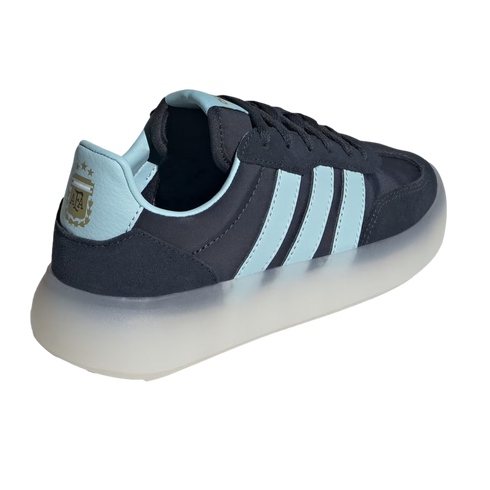 A navy blue and light blue sneaker shown from a rear three-quarter angle against a black background. It features three light blue side stripes, a light blue heel tab with a gold Argentina national football team (AFA) crest and three stars, and a thick, tr