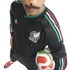 High-angle shot of a man with a mustache wearing a black Mexico soccer jersey and holding a soccer ball against a white background.