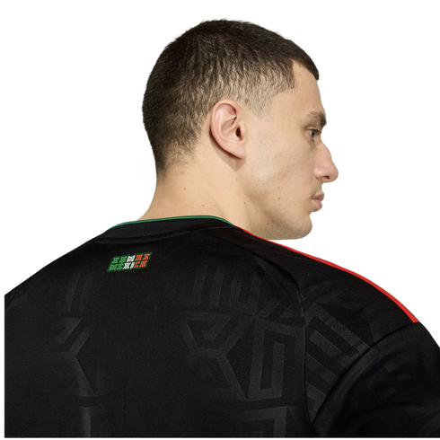 Rear profile of a man wearing a black Mexico soccer jersey with red shoulder stripes and "SOMOS MÉXICO" on the back neck.