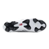 Bottom view of a white New Balance soccer cleat featuring black molded studs and a red logo on the sole.