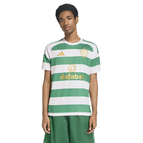 A man modeling a green and white hooped Celtic FC football jersey with gold logos and matching green shorts.