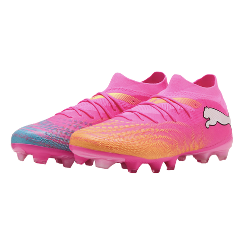A pair of pink Puma soccer cleats with a sock-like fit. One boot features a teal-patterned toe, and the other an orange-patterned toe.