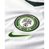 Close-up of a white Nigeria football jersey featuring the Nigeria Football Federation crest and a green Nike swoosh logo on textured, ribbed fabric.