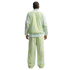 Rear view of a person with braided hair in a light green and yellow marbled-print tracksuit. The loose-fitting jacket and pants feature mesh paneling on the sleeves and sides.
