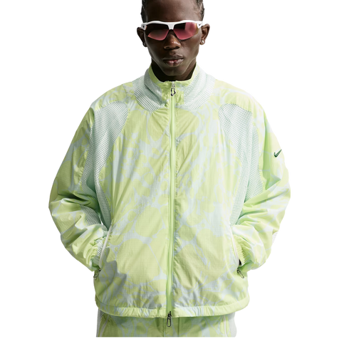 A person wearing white-framed sunglasses and a light green patterned Nike zip-up jacket with mesh panels, posing against a white background.