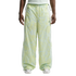 A front view from the waist down of a person wearing baggy, light green and white patterned Nike track pants with white mesh side panels and white sneakers.