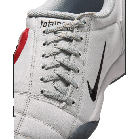 Close-up of a light gray textured Nike sneaker with gray laces and a black swoosh logo on the side.