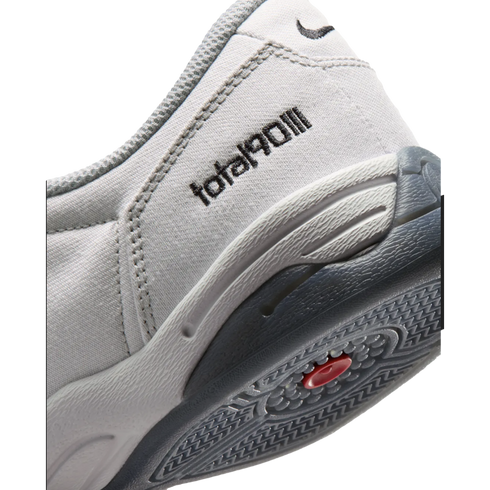 Close-up of a grey Nike Total 90 III shoe's heel featuring the "total90III" logo, a small swoosh, and a textured grey and black sole with a red accent.