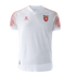 White Kelme soccer jersey for the Jordan national team featuring red patterned shoulders, the team crest, and a red brand logo on the chest.