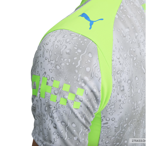 Close-up of a Puma jersey sleeve featuring a gray water droplet pattern, a neon green panel with a blue Puma logo, and lime green blocky graphics.