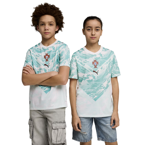 A boy and a girl stand side-by-side against a black background, wearing matching sports jerseys. The jerseys are white with a teal wave-like pattern on the upper half, featuring a team crest and a Puma logo in the center. The boy on the left has curly hai