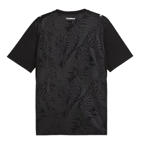 The back of a black t-shirt featuring a subtle, tonal pattern of repeating silver ferns. The word "AOTEAROA" is printed in white block letters below the collar, and a white Puma logo is on the right shoulder.