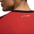 A close-up photograph shows the upper back and neck of a person wearing a red sports jersey. The jersey features a black collar and a stylized gold inscription of the word "Egypt" in Arabic (مصر) on the upper back.