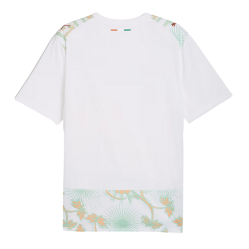A back view of a white soccer jersey featuring a small orange, white, and green flag on the back of the neck. Light green and gold floral patterns decorate the shoulders and bottom hem, with gold Puma logos on each shoulder.