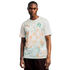 A Black man stands against a plain black background, wearing a white Côte d’Ivoire national football team jersey by Puma. The jersey features an orange Puma logo on the right chest and the team crest on the left, with a light green and orange graphic patt