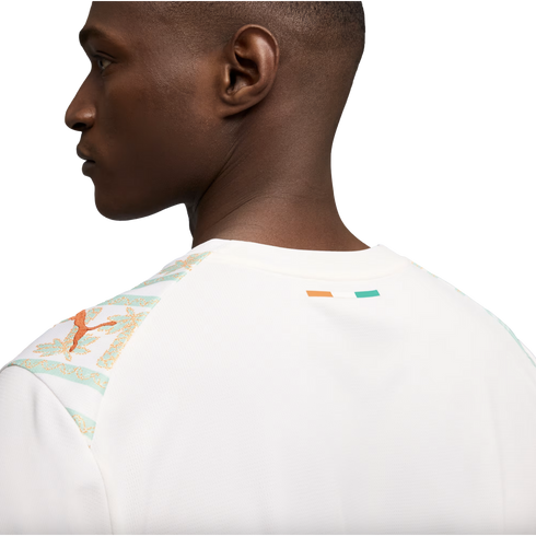 A close-up profile view from the back of a man wearing a white Puma jersey featuring mint green and orange patterned shoulders and a small Ivory Coast flag on the back collar.