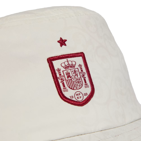 Close-up of a white bucket hat featuring the embroidered red and white Spain national football team crest with a red star above it.