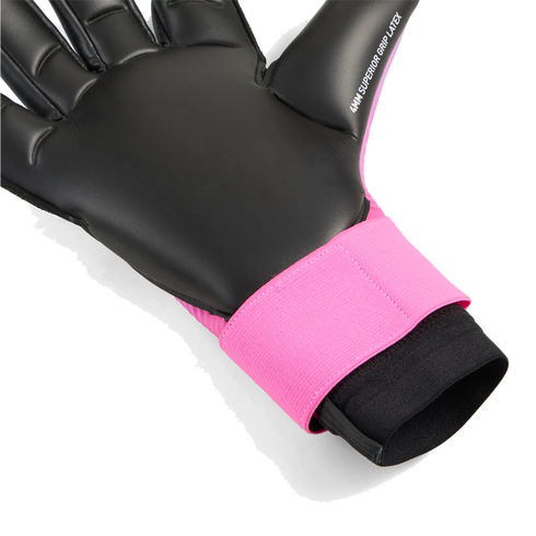 Close-up of a goalkeeper glove featuring a black latex palm and a bright pink wrist strap. The thumb is labeled "4MM SUPERIOR GRIP LATEX."