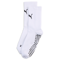 White Puma crew socks with black logos on the ankles and grey non-slip grippers on the soles, against a black background.
