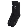 A pair of black crew socks with white Puma logos, ribbed ankles, and grey non-slip grip dots on the soles, set against a black background.