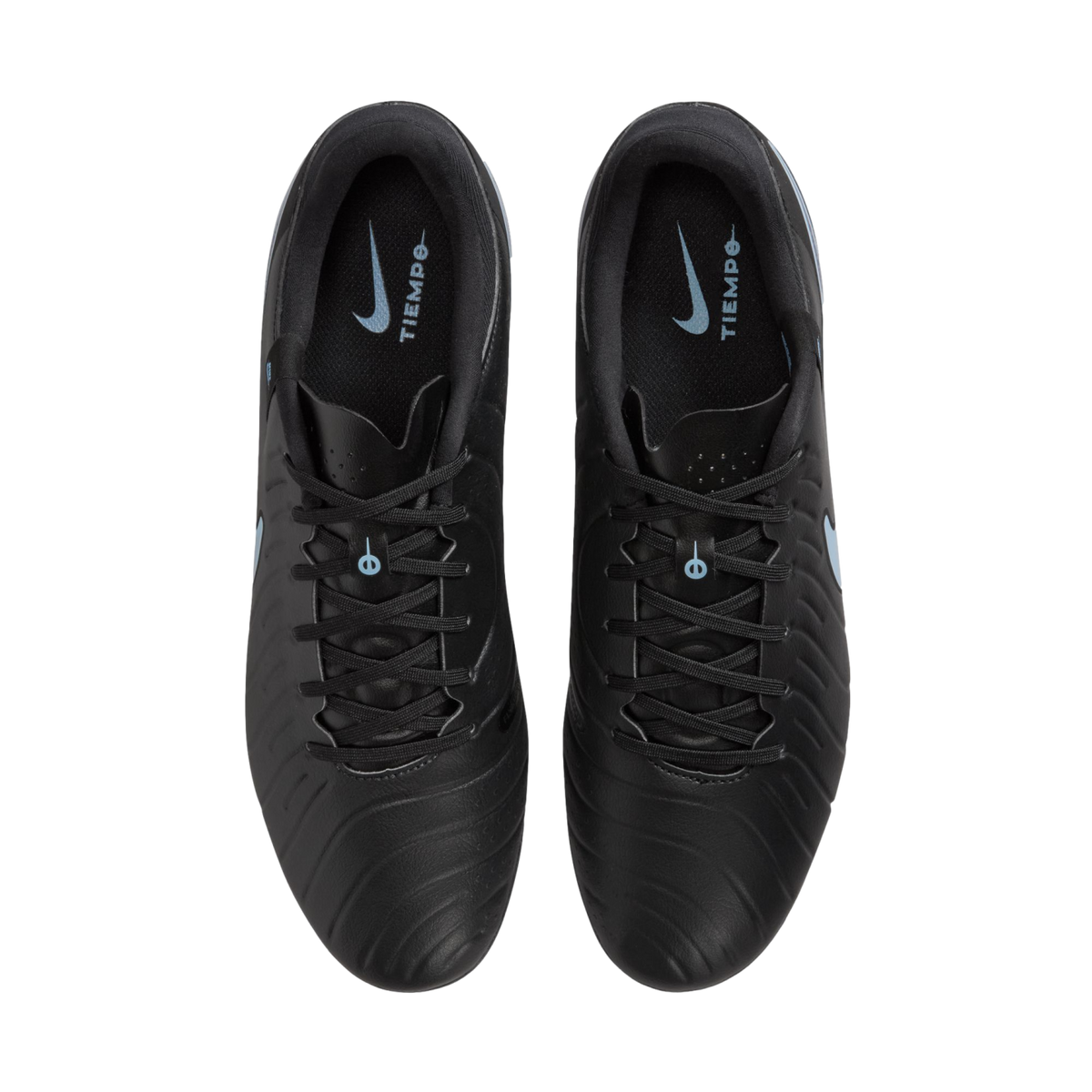 Overhead view of black Nike Tiempo soccer cleats on a black background, showing light blue logos on the inner soles.