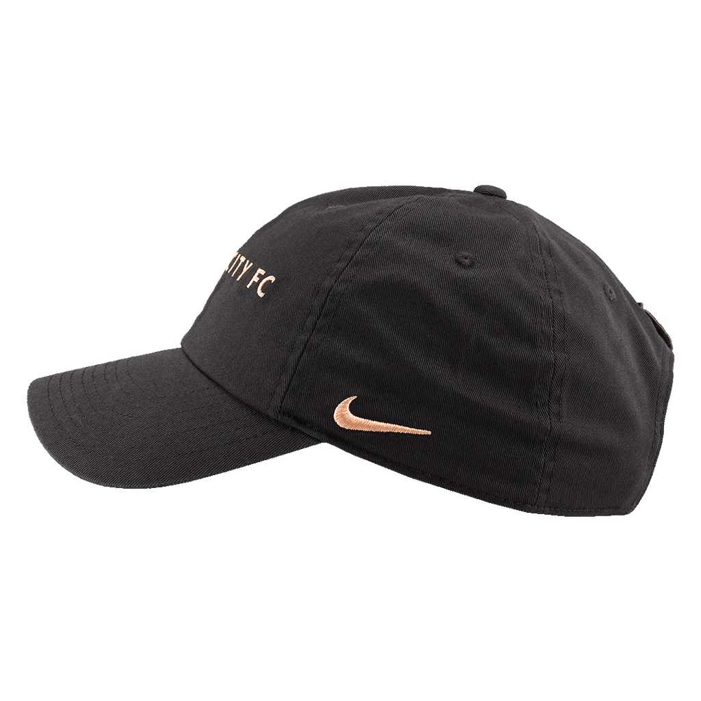 Side profile of a black baseball cap with rose-gold embroidery, featuring a Nike swoosh on the side and "CITY FC" on the front crown.
