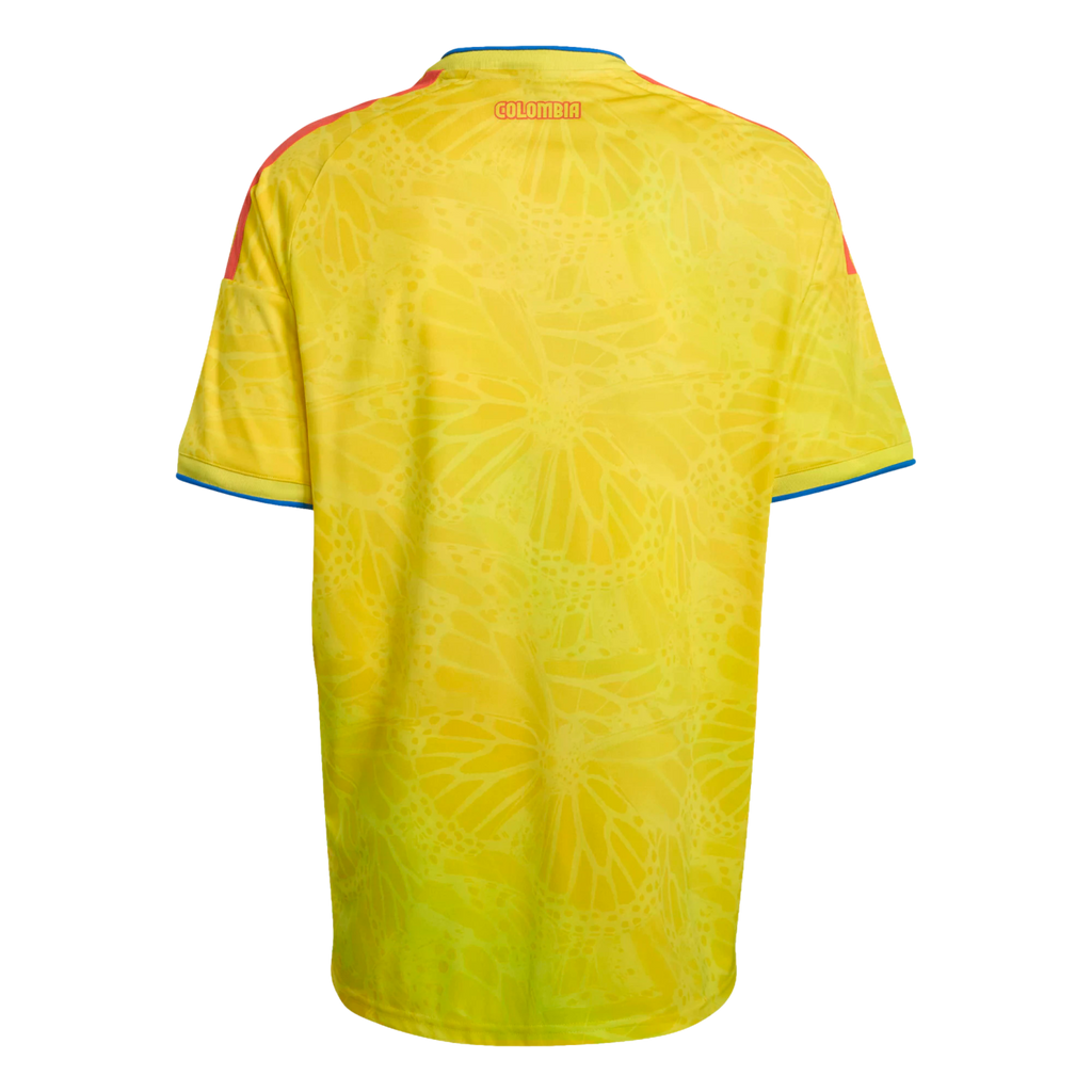 Back of a yellow Colombia soccer jersey with a subtle butterfly wing pattern, red shoulder stripes, and "COLOMBIA" in red text near the collar.