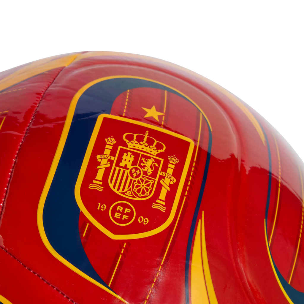 Close-up of a glossy red soccer ball featuring the Royal Spanish Football Federation crest in yellow and red, with a single gold star above it.