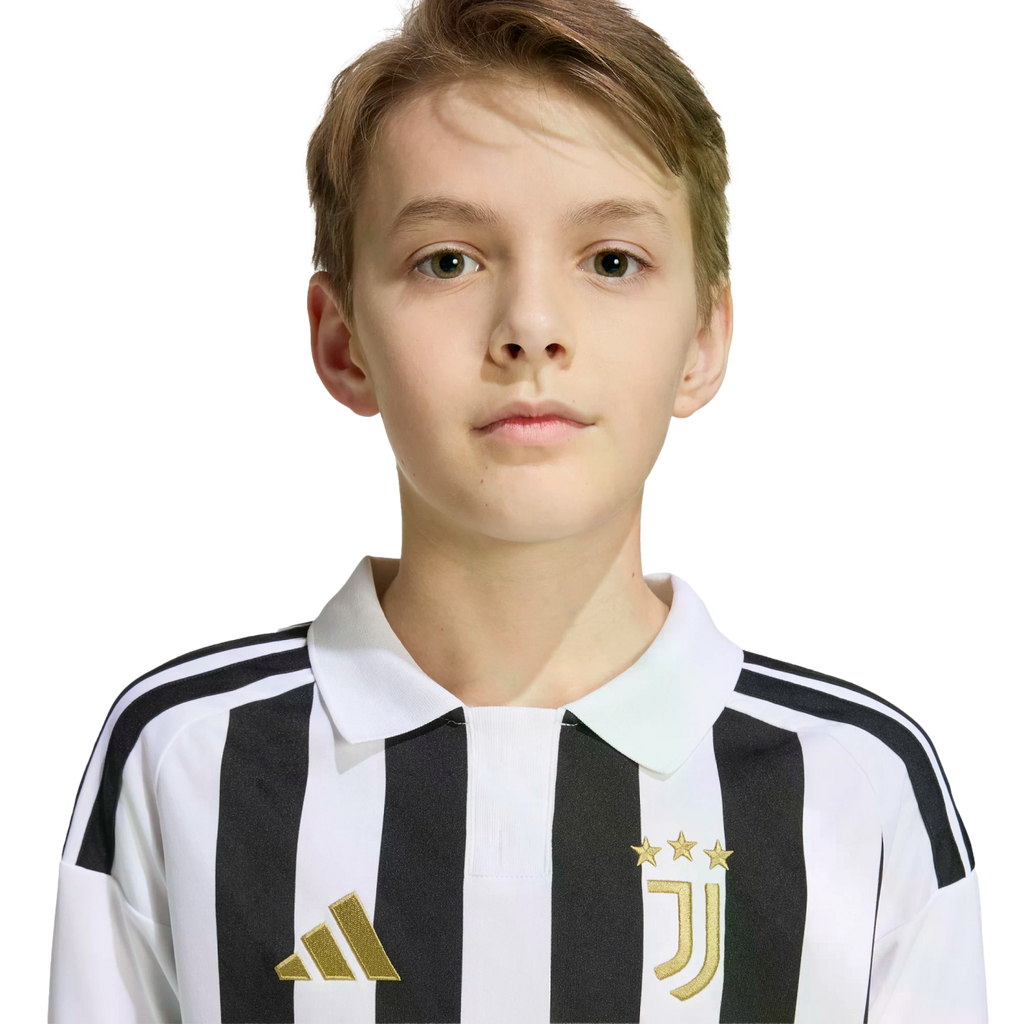 Portrait of a young boy with light brown hair wearing a black and white striped Juventus jersey against a white background.