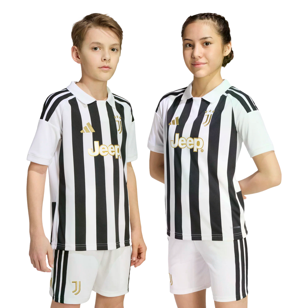 Two young people wearing matching black and white striped Juventus football kits with gold logos, standing against a plain white background.